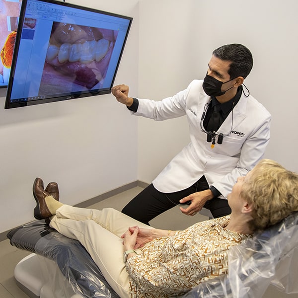 Dr. Calos using a digital image to explain to a woman about her oral health