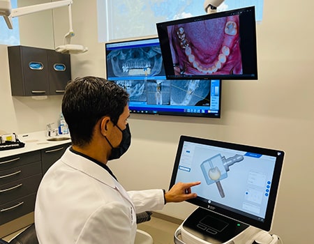 Dr. Melendez reviewing the design of dental implants on a monitor